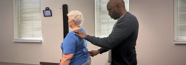 Dr. James Cooley examining a patient's back while the patient stands straight