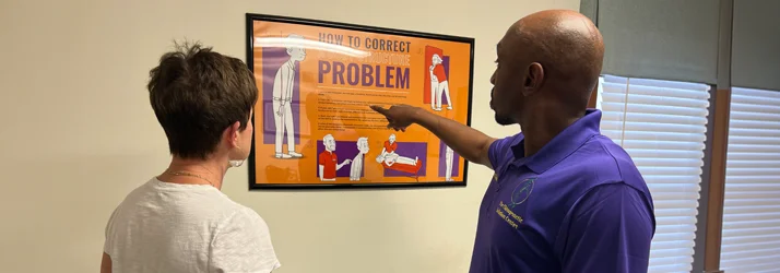 Dr. Cooley discussing posture with a patient, using a poster as a reference
